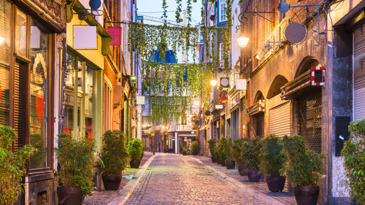 A picturesque, narrow cobblestone street lined with historic buildings and hanging greenery, capturing the essence of cultural walking tours 2026 as a museum without walls.